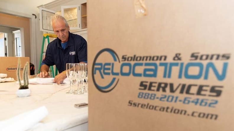 A mover carefully packing drinkware before boxing