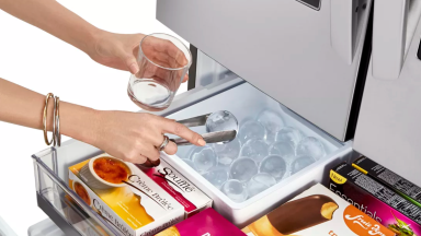 Woman's hands scooping up round ice from a freezer