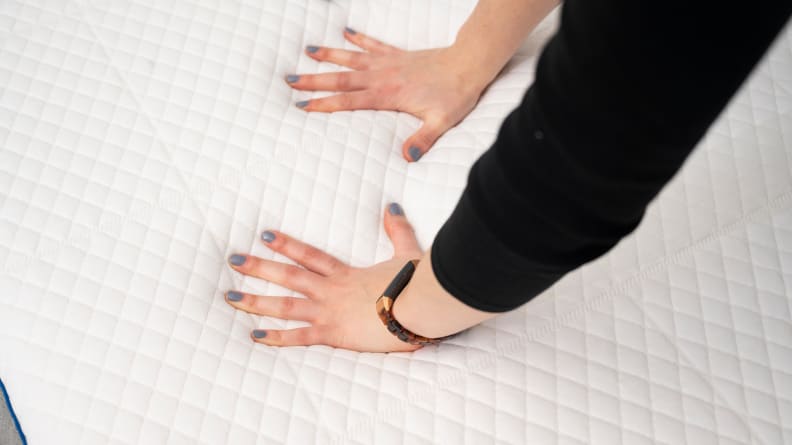 a woman's hands press into the surface of the Nectar Mattress