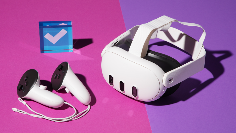 A white vr headset with two controllers on a pink and purple background
