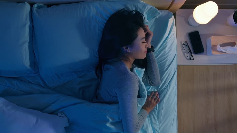a woman asleep with her phone beside the bed