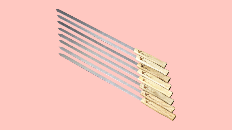 Eight G & F Stainless Steel BBQ Skewers on a pink background.
