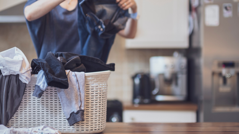 A person sorts laundry on a kitchen countertop.