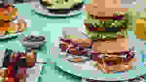 蓝色桌布上摆着素食汉堡、烤串和其他不清晰的盘子，盘子上放着食物
