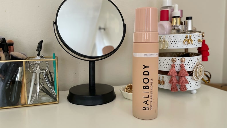 A bottle of self tanner stands on a vanity.