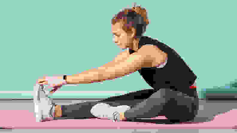 A person stretching on a mauve lululemon yoga mat.