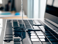 A stream of water spills on a laptop keyboard