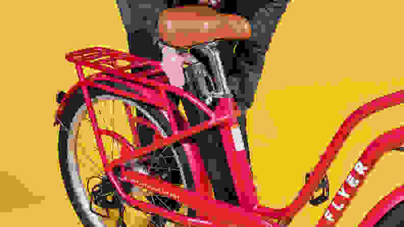 A person removes the Radio Flyer Cruiser Step-Thru’s battery from its frame mounting behind the saddle.