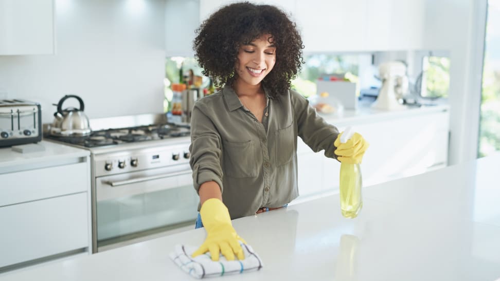 A person scrubs a quartz countertop in a kitchen.