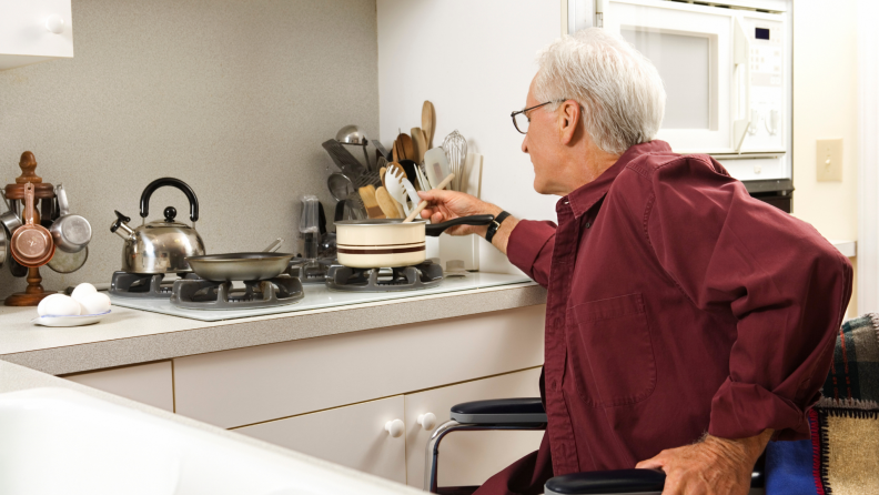 A man in a wheelchair cooks a meal in a kitchen.