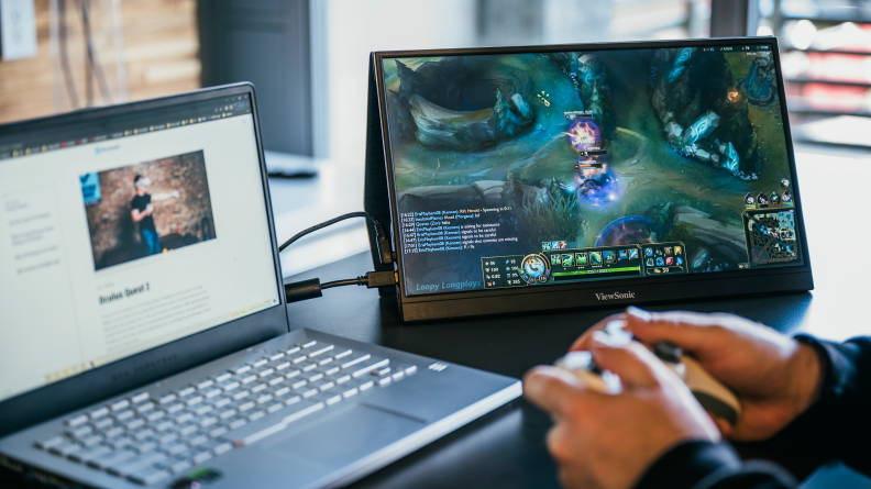 A person playing a video game on a laptop with a connected, extra monitor.