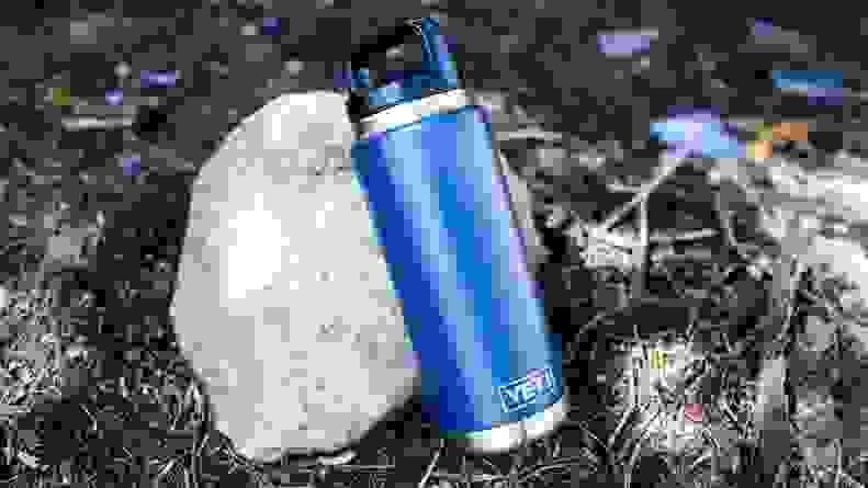 A water bottle leaning against a rock.