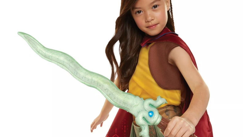 Little girl in a Raya costume holding a plastic sword