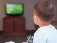 Young child holds remote and looks at a television