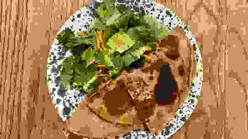 一个全麦quesadilla和沙拉在一个斑点的白色和灰色板材。