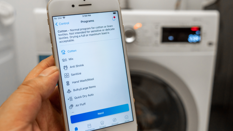 Person holding smartphone in order to control dryer.