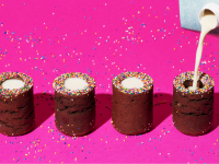 Milk being poured into cylindrical desserts on a neon pink background