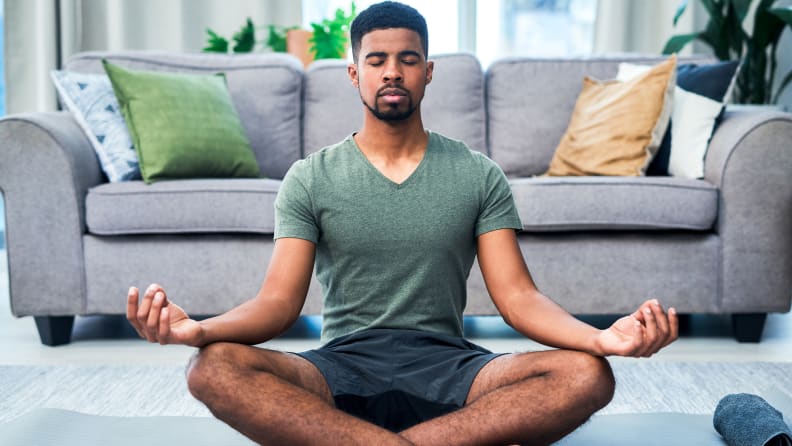 A man meditating in the living room.