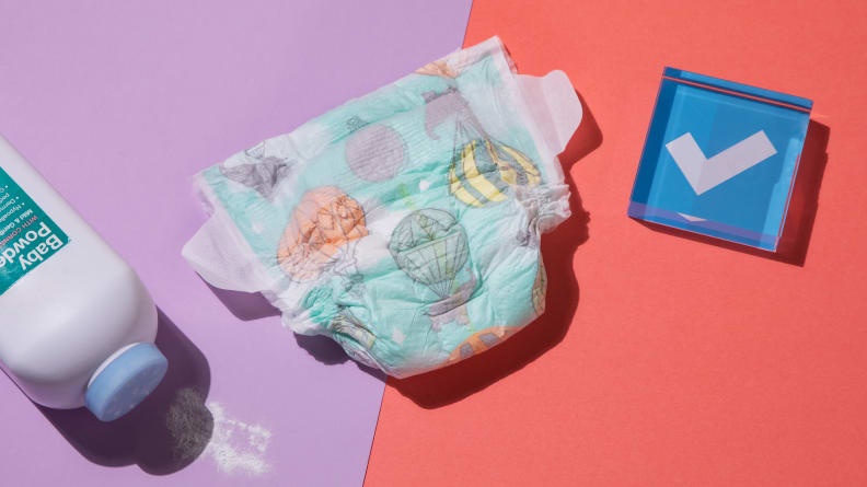 A single Honest diaper in the middle of a bottle of talcum powder and a blue paperweight.