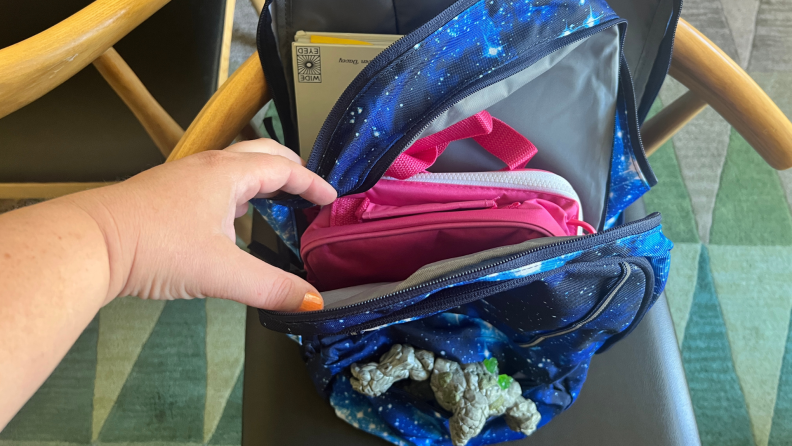 Person using hand to display each compartment within the Lands' End XL backpack in Blue Galaxy Space color pattern.