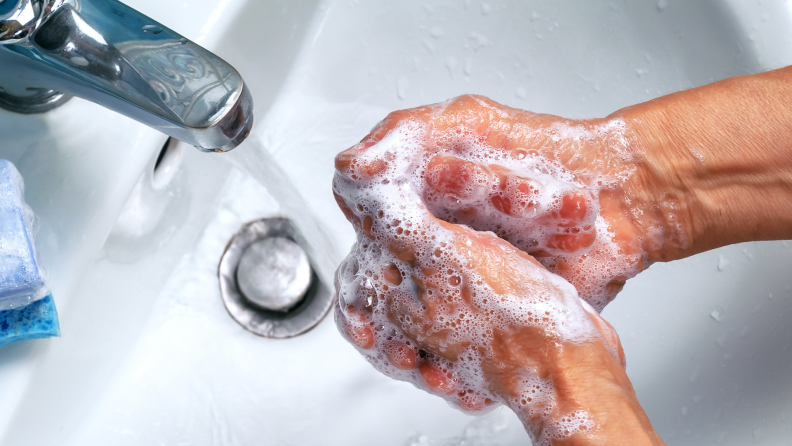A person washes their hands with soap.
