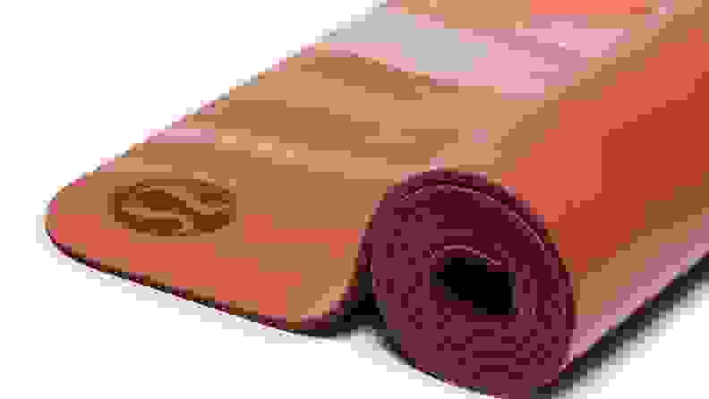 Red colored exercise mat rolled up on white background.