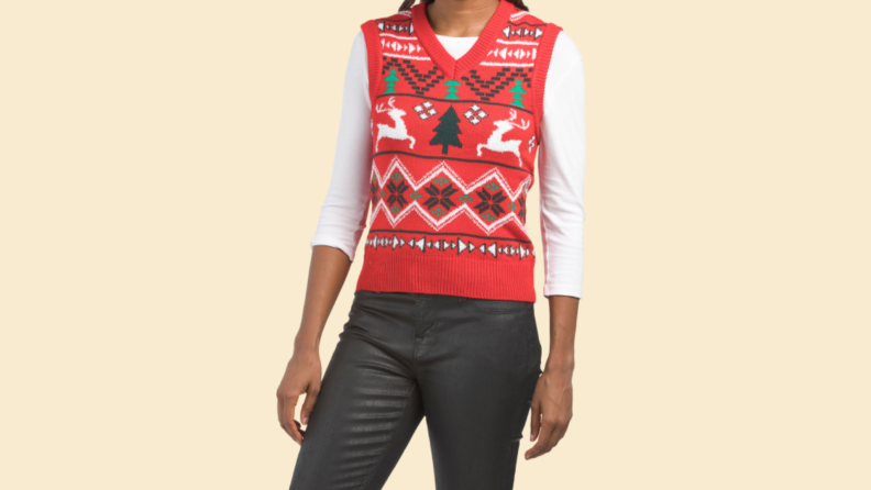 A woman wears a red Christmas vest with holiday patterns on it.