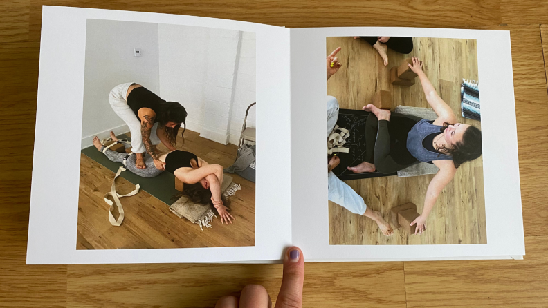 A photo book open to a page with two images and a person's finger holding the book open