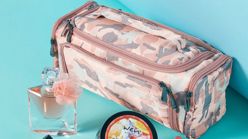 Pink camouflage overnight duffle bag next to beauty prodcts.