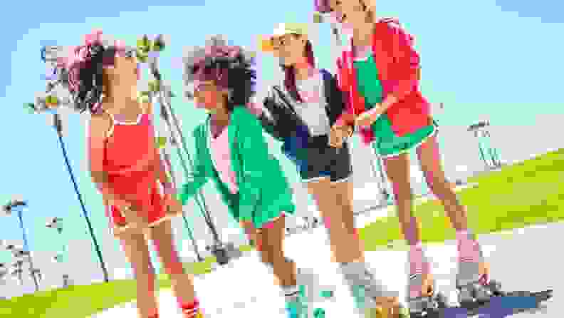 A group of girls wear colorful clothes as they rollerskate
