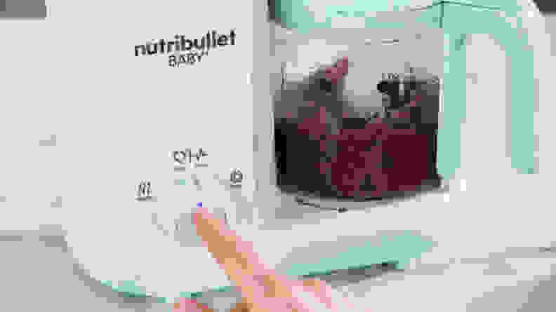 A person pressing a dial on the Nutribullet Baby Steam + Blend.