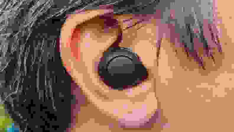 这款黑色圆润的索尼WF-C500耳塞戴在一个头发棕银色的男人的耳朵里。