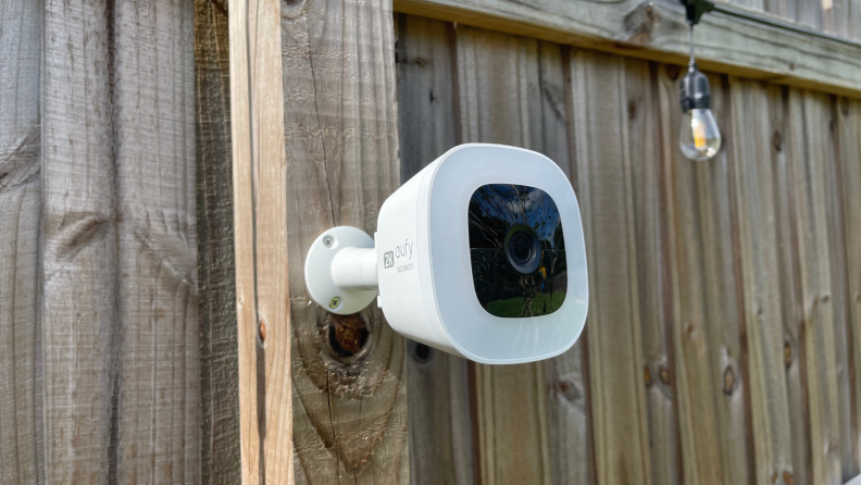 The Eufy SoloCam L20 hangs on a wood fence.