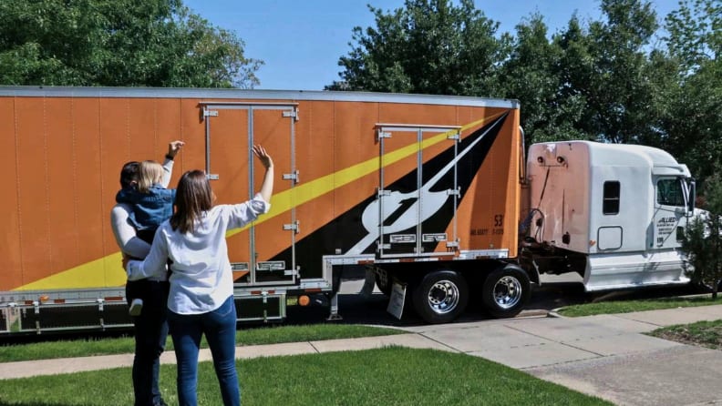 A family waving a moving truck goodbye