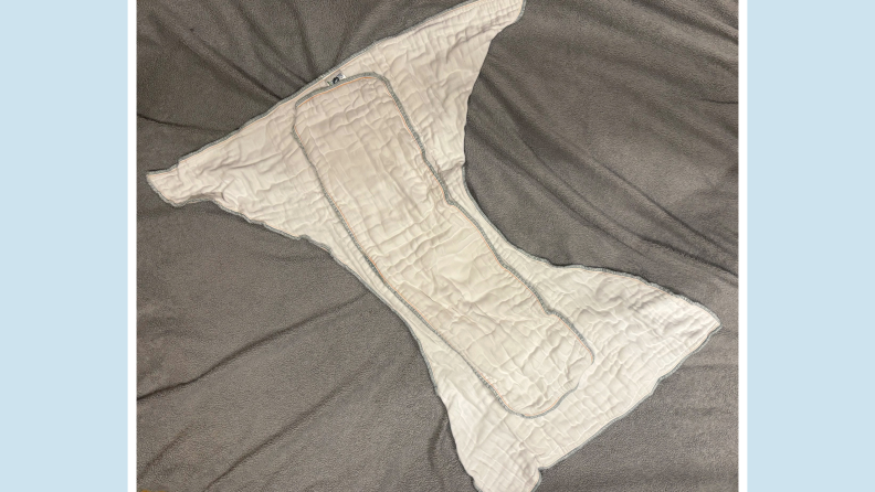 White cloth diaper laid out flat on gray fabric surface.