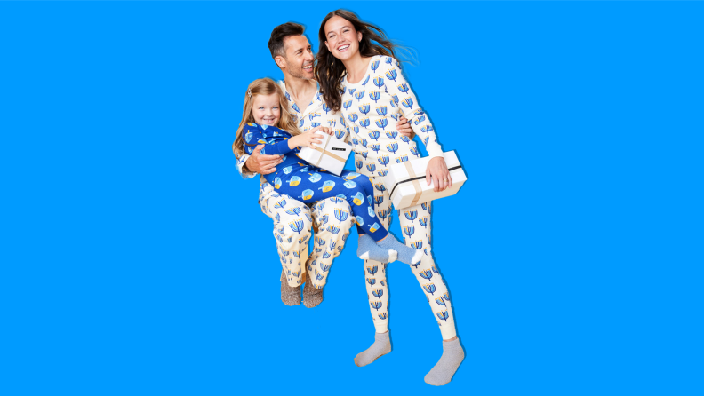 A family wearing Hanna Andersson Hanukkah matching family pajamas on a blue background.