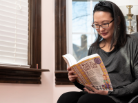 A pregnant woman reads a book about what to expect in the first year of motherhood.