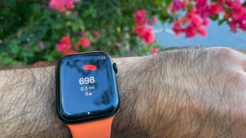 A person checks an Apple Watch fastened to their wrist featuring the Pedometer app.