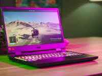 The Nitro 5 sits on a wooden table with a pink backlight shining on it.