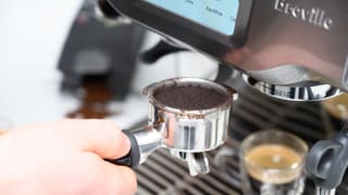 A person places espresso in an espresso machine