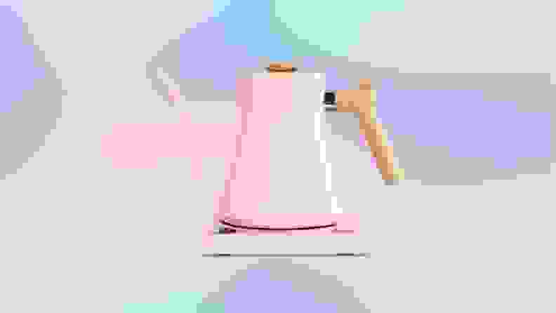 A pastel pink gooseneck electric kettle against a pastel rainbow gradient background.