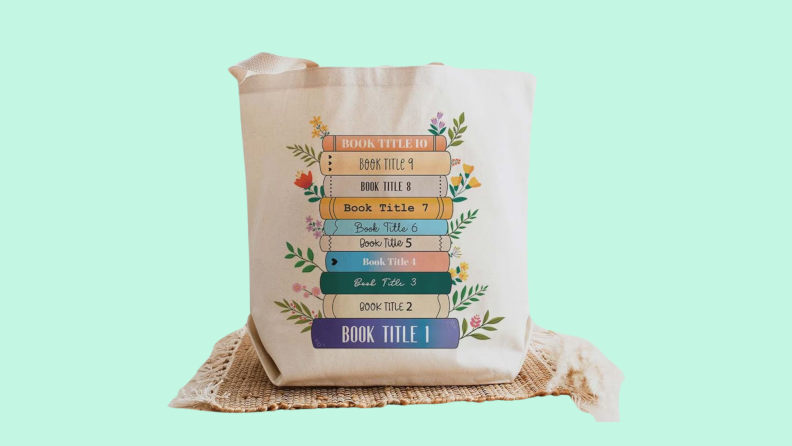 A white tote bag with colorful writing on it on a green background.