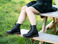 女孩坐野餐桌穿doc martens靴子。