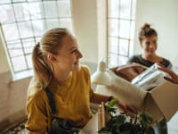 two women moving boxes up a staircase