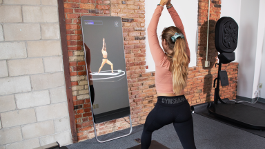 A woman lunging in front of the Fiture smart workout mirror.