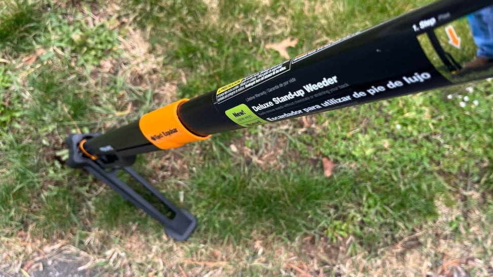 A close-up view of the Fiskars Deluxe Stand-up Weeder in a grassy yard.