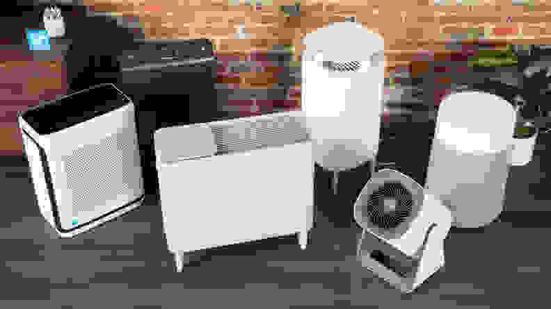 A selection of multiple air purifiers laid out on a row on the floor.