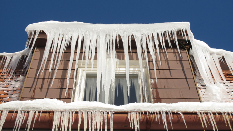 Icicles and snow hang on a roof.