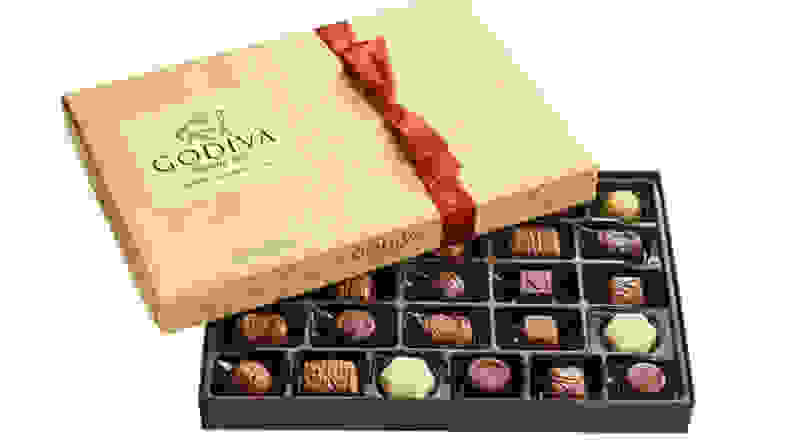 Godiva box of chocolates with the lid partially removed, revealing several artisan chocolates