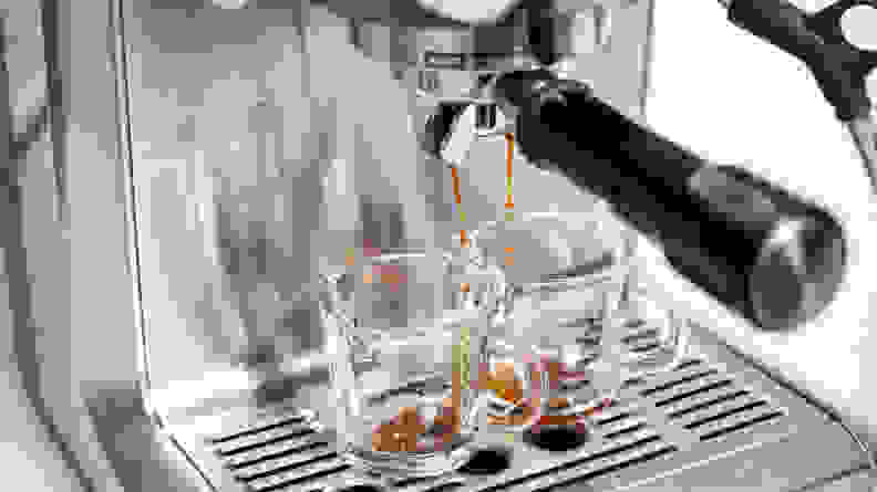 Espresso being brewed into two glass mugs from a stainless steel machine.